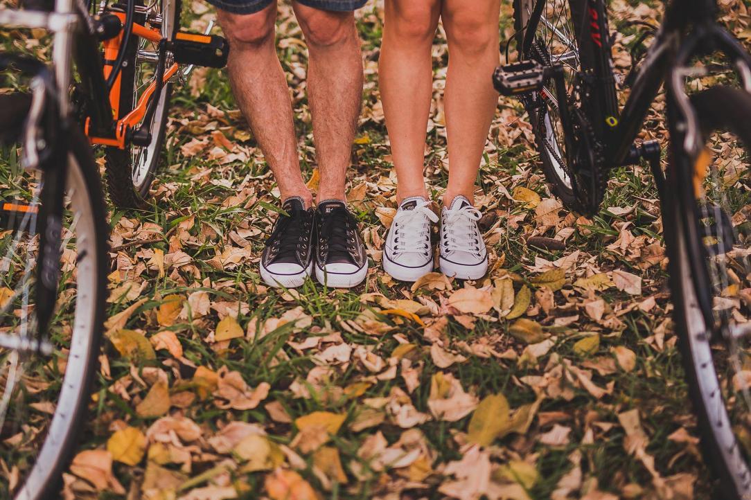 Two women standing  in between their bikes on a leaf covered lawn