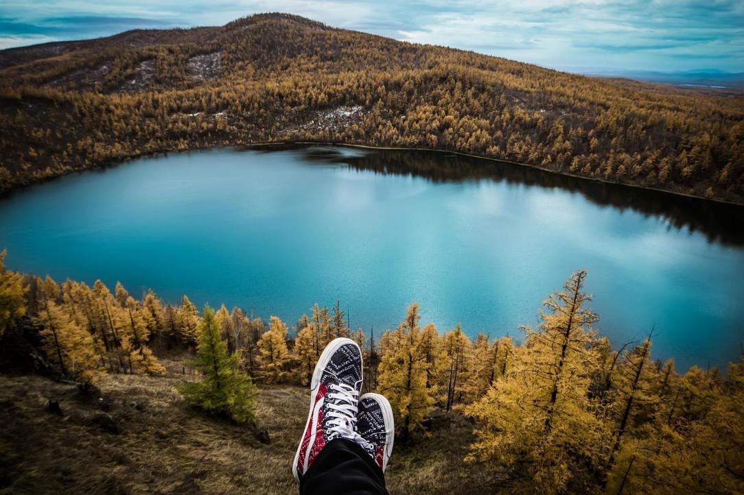 Point of view sitting with legs crossed over a mountain lake