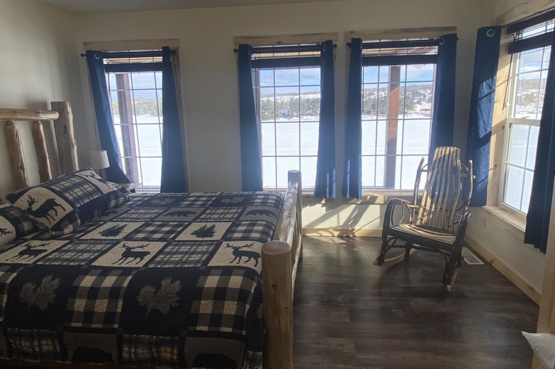 Queen bed with bathroom and windows overlooking the water
